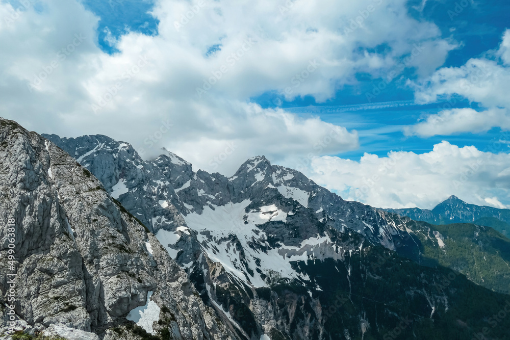 Scenic view from Mala Baba on rocky, sharp, cloud and snow covered mountain summit peaks of Kamnik Savinja Alps in Carinthia, border Austria Slovenia. Spring in Vellacher Kotschna. Via Ferrata. Breath