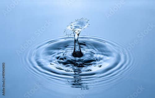Splash and umbrella on blue background. Reflection on the surface of the water.