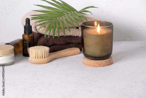 Skin care product for oil face massage and flowers on white table. Eco friendly organic reusable self care accessories.