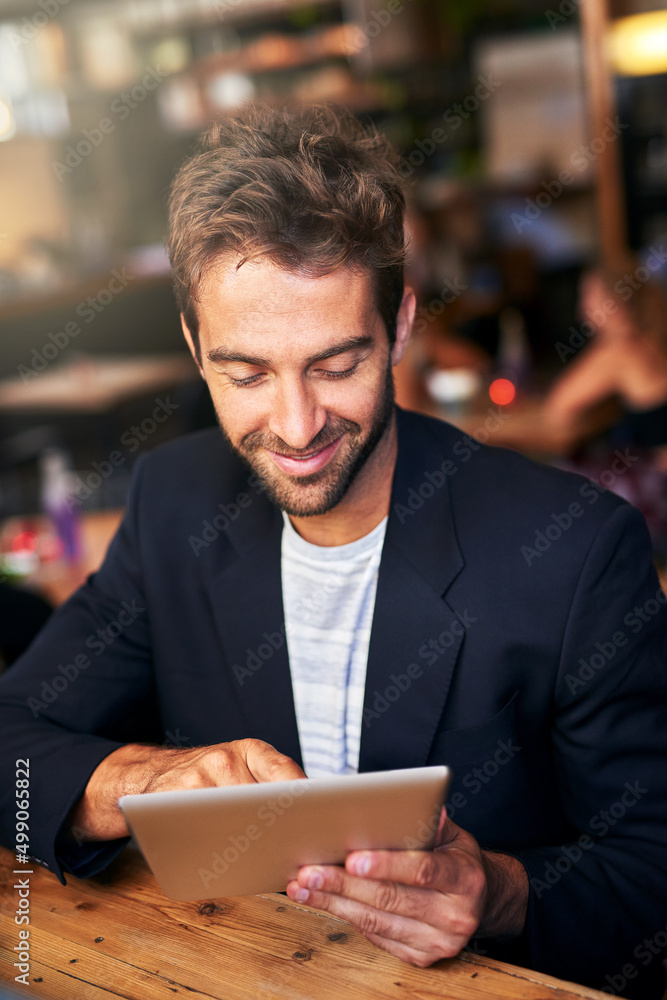 Connected on the go. Shot of a handsome young man using a digital tablet in a cafe. Connected on the go. Shot of a handsome young man using a digital tablet in a cafe.