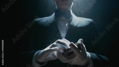 Close-up of a Suited Magician's Hands Performing Sleight of Hand Card Tricks. Cards fly and turn over in the air. Slow Motion. Background is Black.