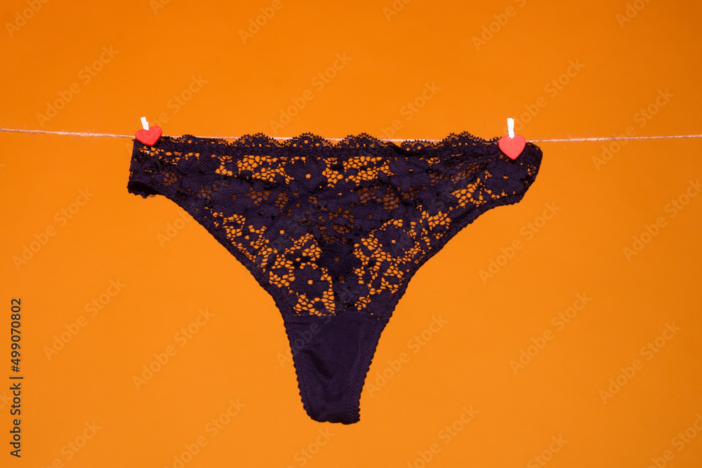 Lace panties. The sexy panty isolated on the yellow background. Black silk  lacy panty, woman underwear, sexy lingerie. Thong bikini panties underwear  lingerie. Stock Photo