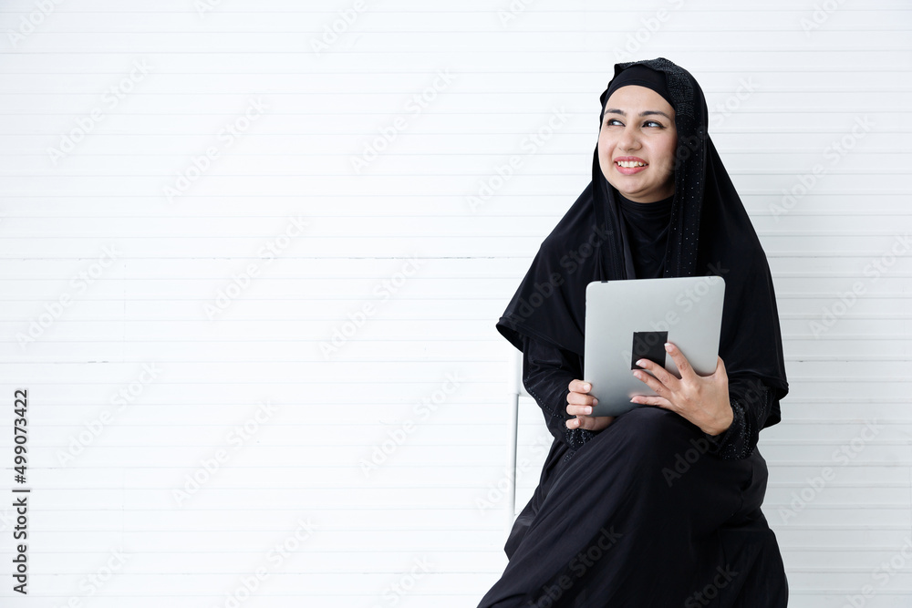 muslim woman using tablet computer on white wall background muslim woman using tablet computer on white wall background