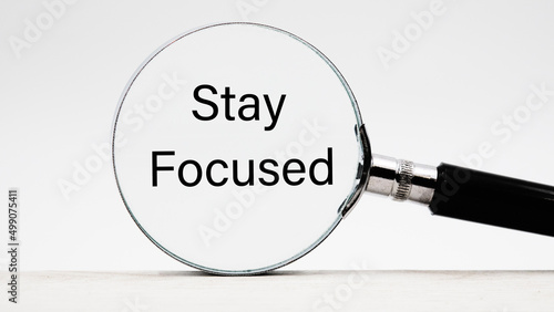 Phrase stay focused through a magnifying glass on a light background