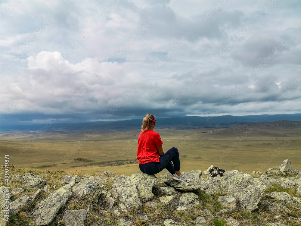 A girl on the background of a picturesque view of the Tazheran steppes. Irkutsk region, Russia. July. 2020. A girl on the background of a picturesque view of the Tazheran steppes. Irkutsk region, Russia. July. 2020.