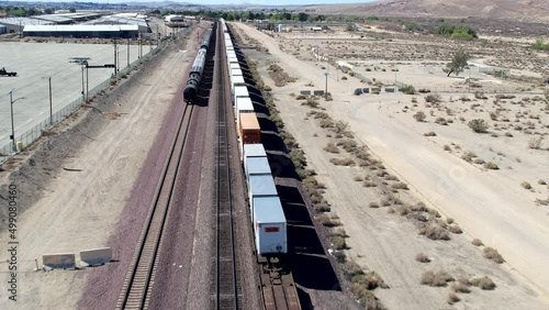 Aerial Drone Following Moving Freight Trains In Barstow Desert In The USA photo