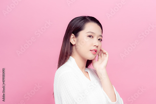 Beautiful young Asian woman touching soft cheek and smile with clean and fresh skin.