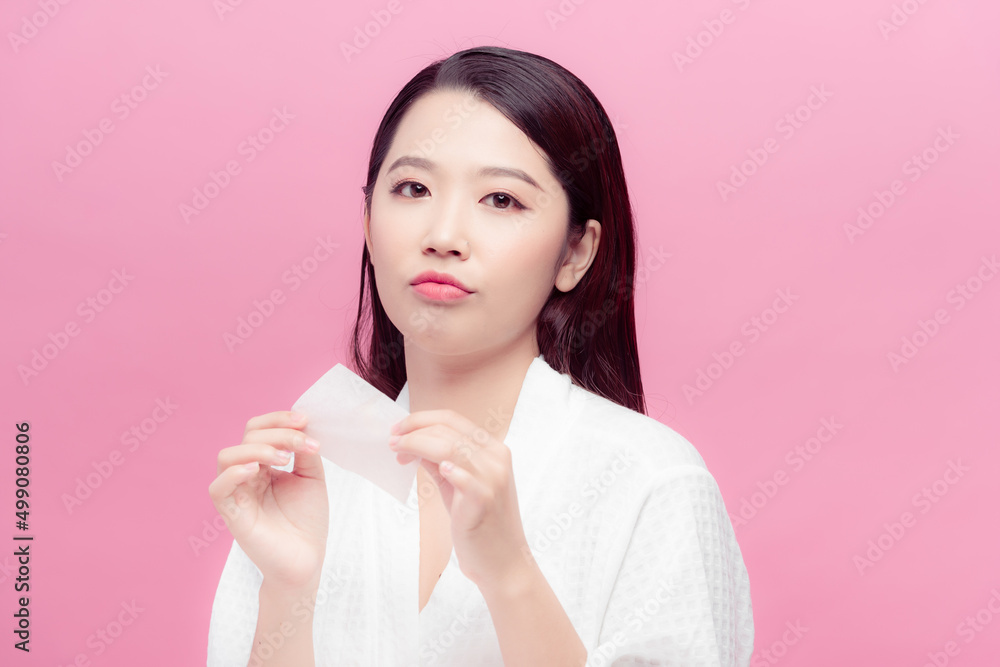 Smiling woman using facial oil blotting paper portrait Smiling woman using facial oil blotting paper portrait