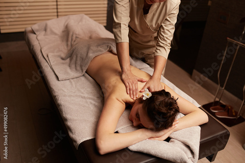 The masseuse gives a body care massage to a young woman. Spa relaxation concept.