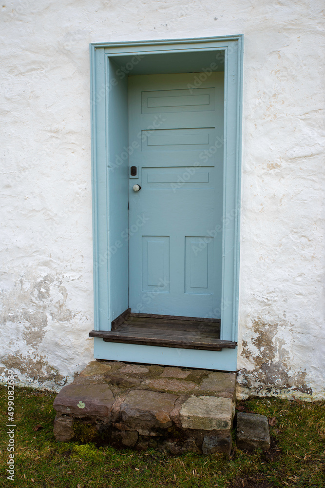 Fototapeta premium Blue colonial wooden door in whitewashed stone cottage