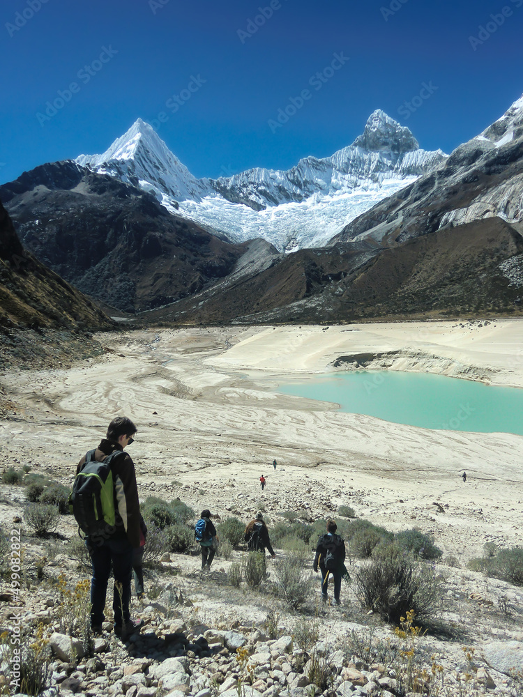 Hikers from the top of a mountain in the Andes in the background a beautiful lake and blue sky
