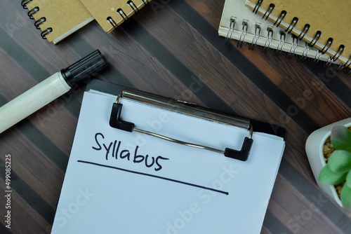 Syllabus write on a paperwork isolated on Wooden Table. photo