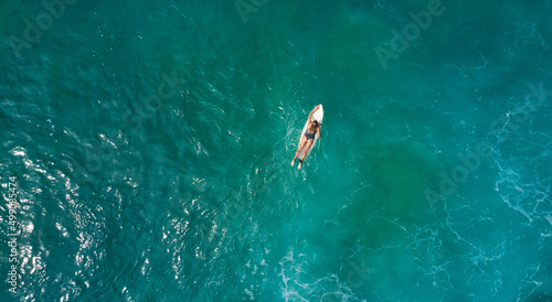 Aerial view of the ocean and surfer girl.