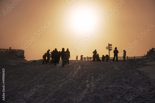 Silhouettes of resting snowboarders and skiers in the ski resort at sunset on the top of the mountain