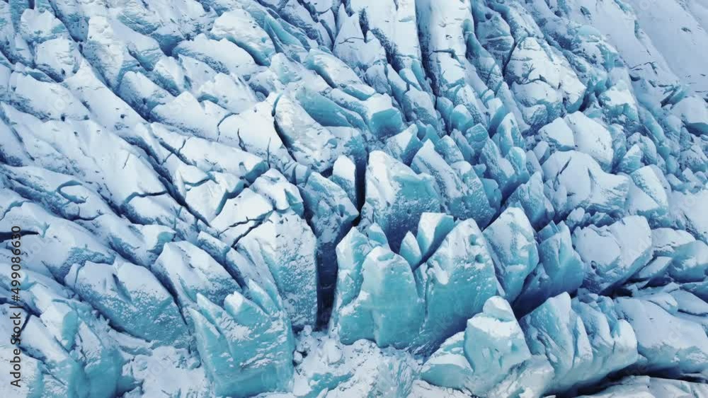 Flying above blue Glacier in Iceland. Deep Crevasses Snowy Ridges Climate Change Global Warming problem.