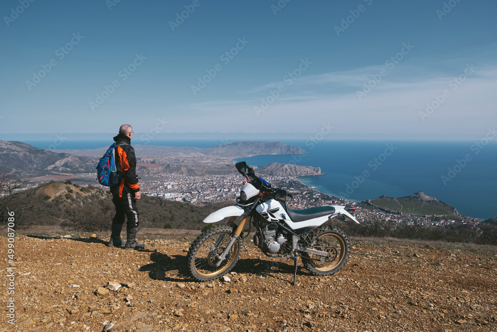 Active elderly man riding enduro motocross motorcycle pit bike in beautiful mountains hills and sea landscape Active elderly man riding enduro motocross motorcycle pit bike in beautiful mountains hills and sea landscape