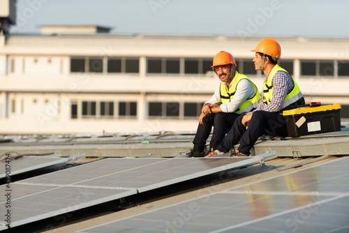 Photovoltaic Technology, Service Engineers inspecting factory roof solar installations in the evening Silhouette technicians inspect and repair solar cells on factory roof