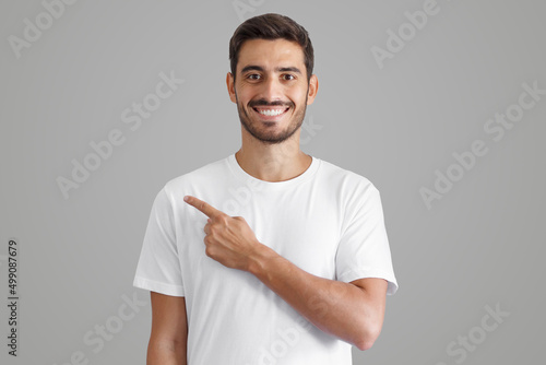 Handsome man in white t-shirt pointing left with finger