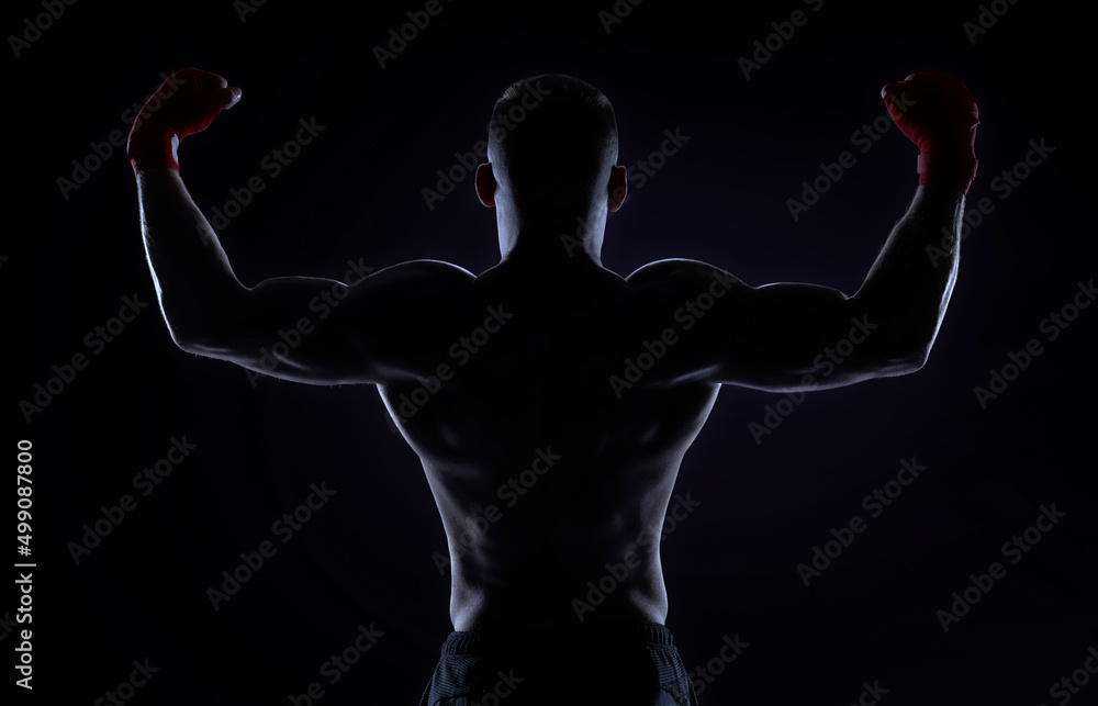 Kickboxer in red bandages raised his hands in victory. Back view. The concept of mixed martial arts.
