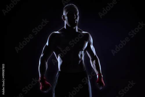 Kickboxer in red bandages posing on a blue background. The concept of mixed martial arts.