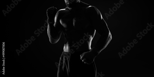 Noname image of a kickboxer on a dark background. The concept of mixed martial arts. © andy_gin