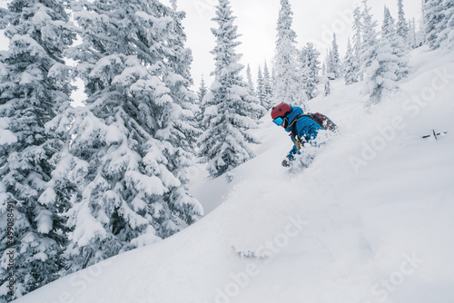 Skier moving in snow powder in forest on a steep slope of ski resort. Freeride, winter sports outdoor