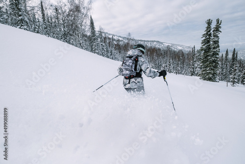 Skier female moving in snow powder in forest on a steep slope of ski resort. Freeride, winter sports outdoor