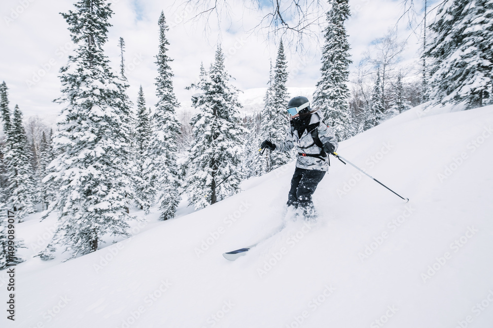 Skier female moving in snow powder in forest on a steep slope of  ski resort. Freeride, winter sports outdoor
