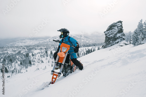 Snowbike rider in mountain valley in beautiful snow powder. Modify dirt bike with snow splashes and trail. Snowmobile sport riding, winter sunny day © Annatamila