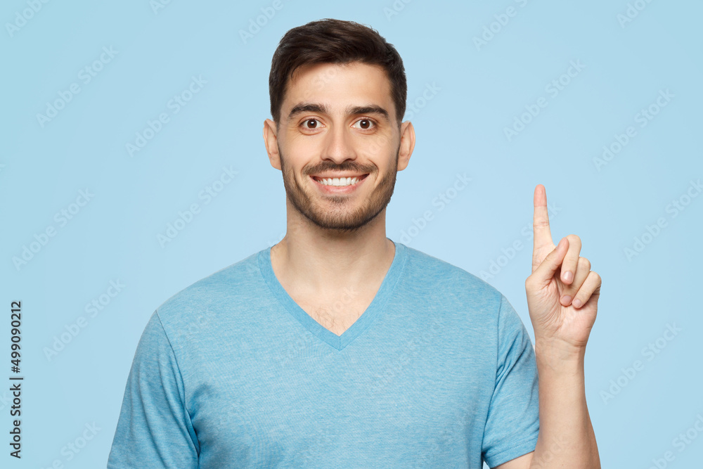 Portrait of excited young man looking at camera, pointing finger up Portrait of excited young man looking at camera, pointing finger up