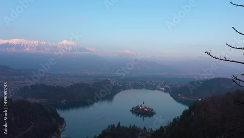 Bled Lake, Marijinega Vnebovzetja Church and Blejski Castle at Sunset. Julian Alps. Slovenia, Europe. View from Velika Osojnica Viewpoint. Aerial View. Drone Flies Forward photo