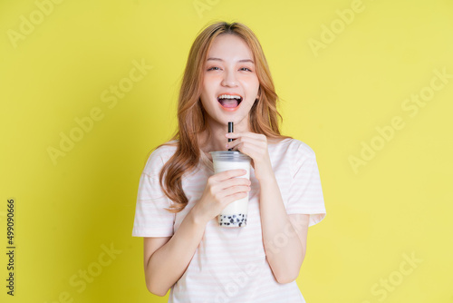 Image of young Asian girl drinking milk tea on yellow background photo