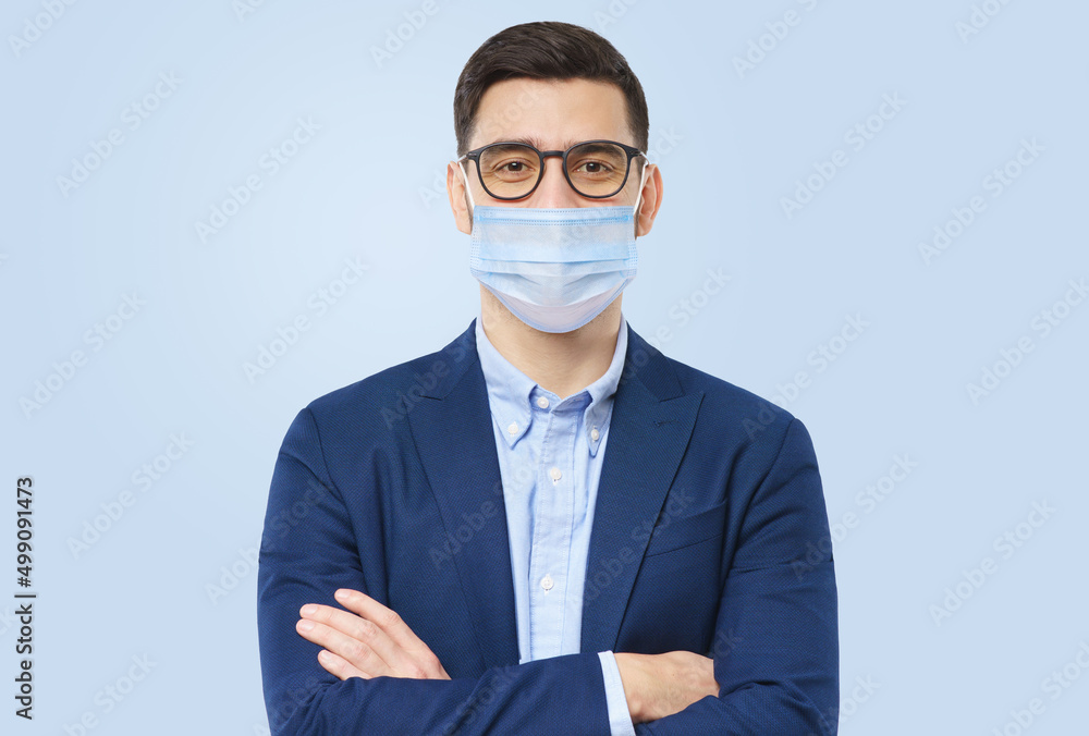 Young man wears glasses and medical mask with crossed arms Young man wears glasses and medical mask with crossed arms