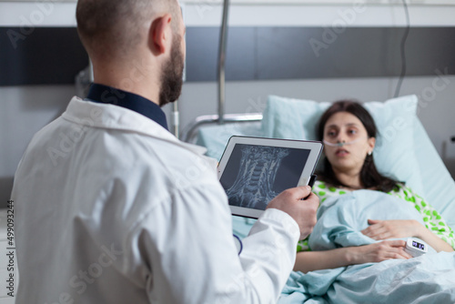 Medical doctor presenting treatment options to patient after diagnosis of throat disease looking at mri on digital tablet. Woman with illness having low oxygen saturation recieving examination.