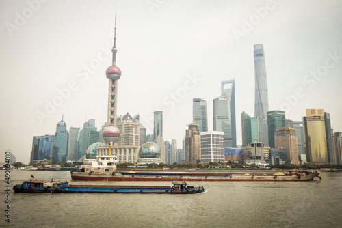 Shanghai Pudong skyline view from the Bund with a cargo ship passing by, Shanghai, China