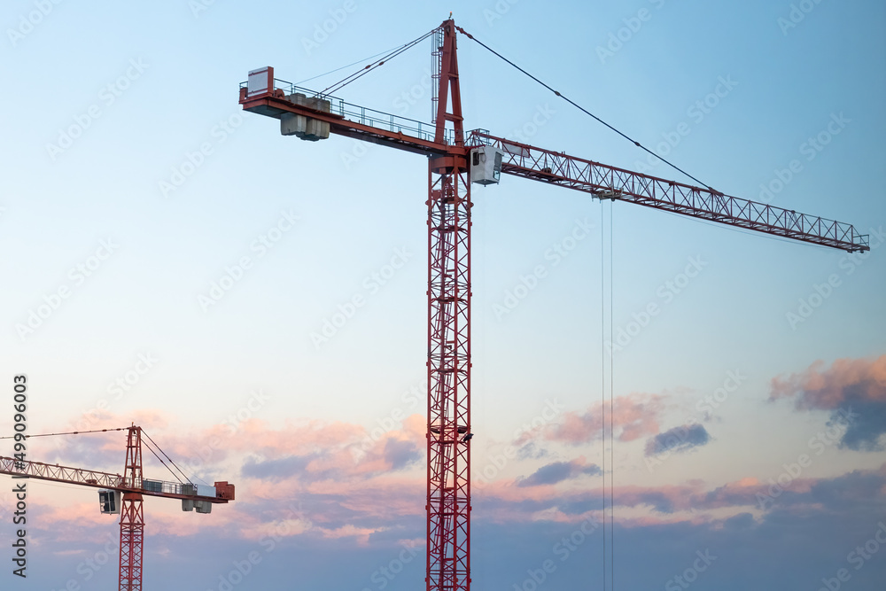 Tall tower cranes on the construction against sunset. Tall tower cranes on the construction against sunset.