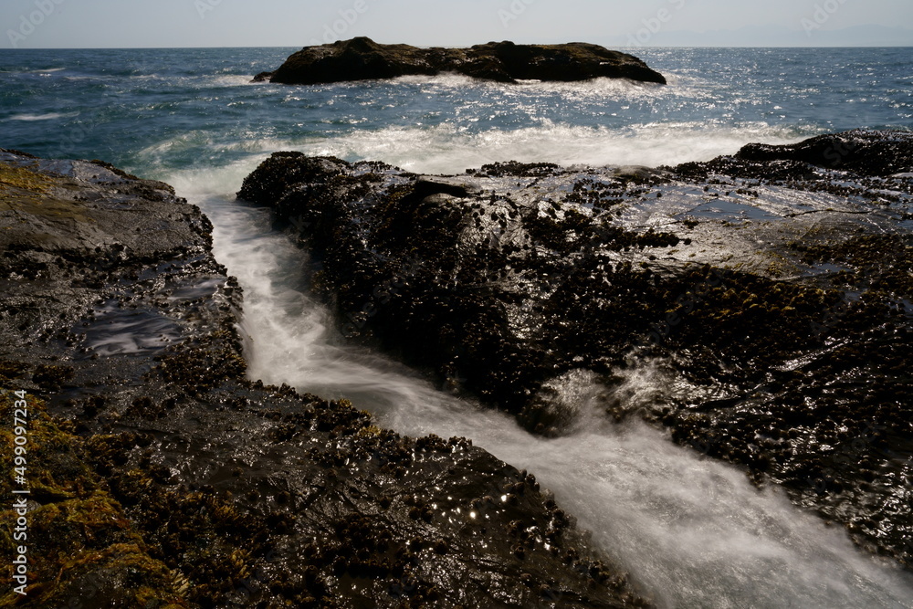 波が打ち寄せる岩場の海岸の風景をスローシャッターで撮
