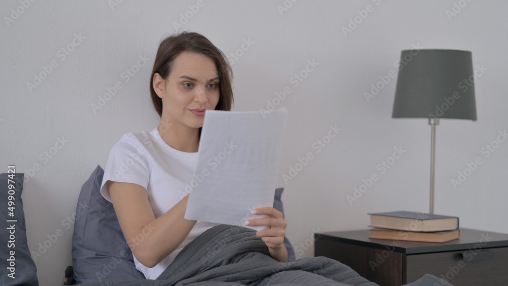 Woman Reading Documents while Sitting in Bed Woman Reading Documents while Sitting in Bed
