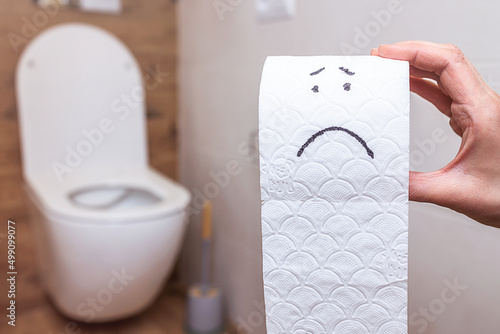 Funny face drawn on a roll of toilet paper on the background of the bathroom