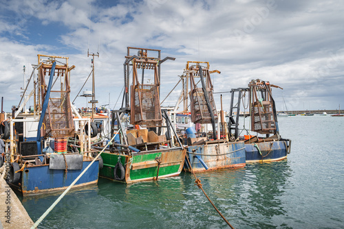 Four small fishing boats with shellfish cages moored in Howth harbour. Phishing and shellfish fishing equipment on fishing boats, Dublin, Ireland