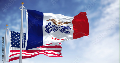 The Iowa state flag waving along with the national flag of the United States of America photo