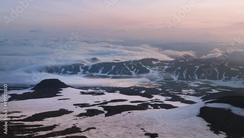 Morning fog floating over the volcanoes and mountains. Kamchatka peninsula, Russia. View from the Gorely volcano. Aerial drone view. Pink sky and snow covered mountains.
 photo