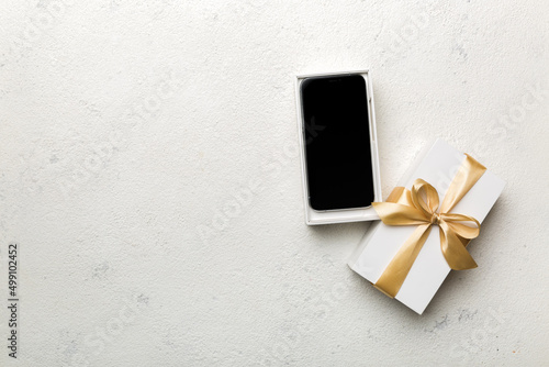 Opened gift box with gold ribbon and smartphone on color background, top view. Blank open box packaging mockup , Template for your design - branding mockup