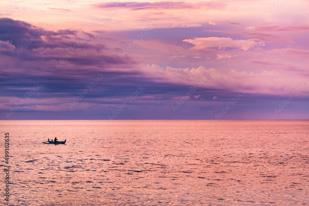 Fototapeta premium Pink sunset on the beach with small boat with fisherman