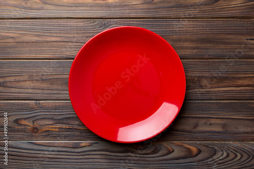 Top view of empty red plate on wooden background. Empty space for your design