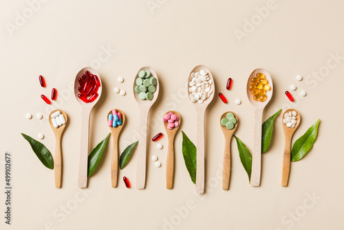 Top view Variety of vitamin and mineral pills in wooden spoon on Colored background. Top view of assorted pharmaceutical medicine pills. Dietary supplement healthcare product photo