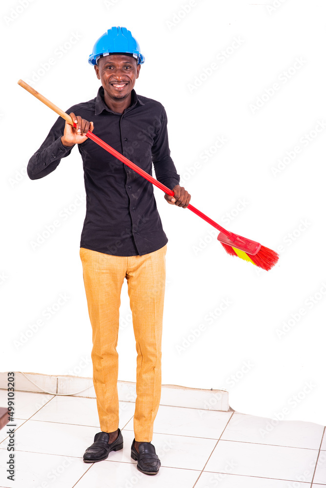 young man engineer holding a broom smiling. young man engineer holding a broom smiling.