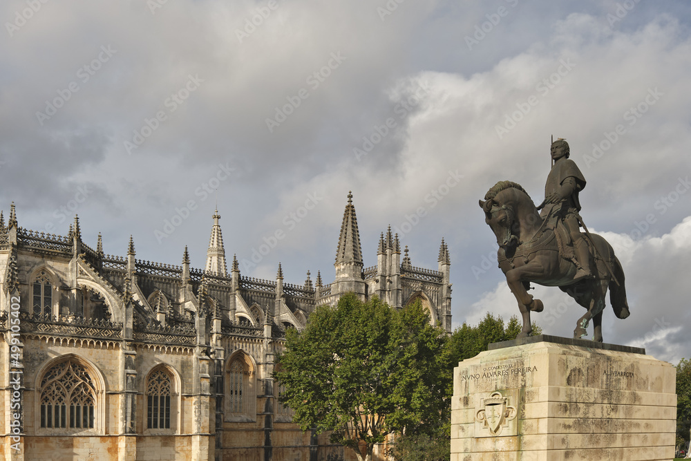 the western façade of the Batalha Monastery facing the large square with its equestrian statue of general Nuno Álvares Pereira in Batalha, Portugal