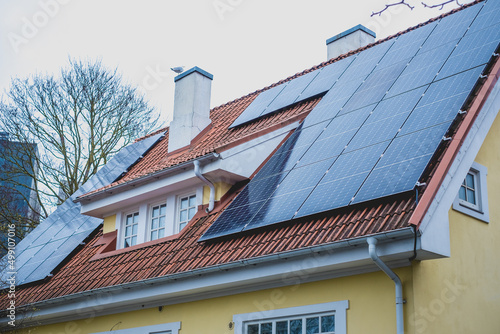 Close-up of solar panels installed on historic building gable roof with chimney. Private home using solar energy.