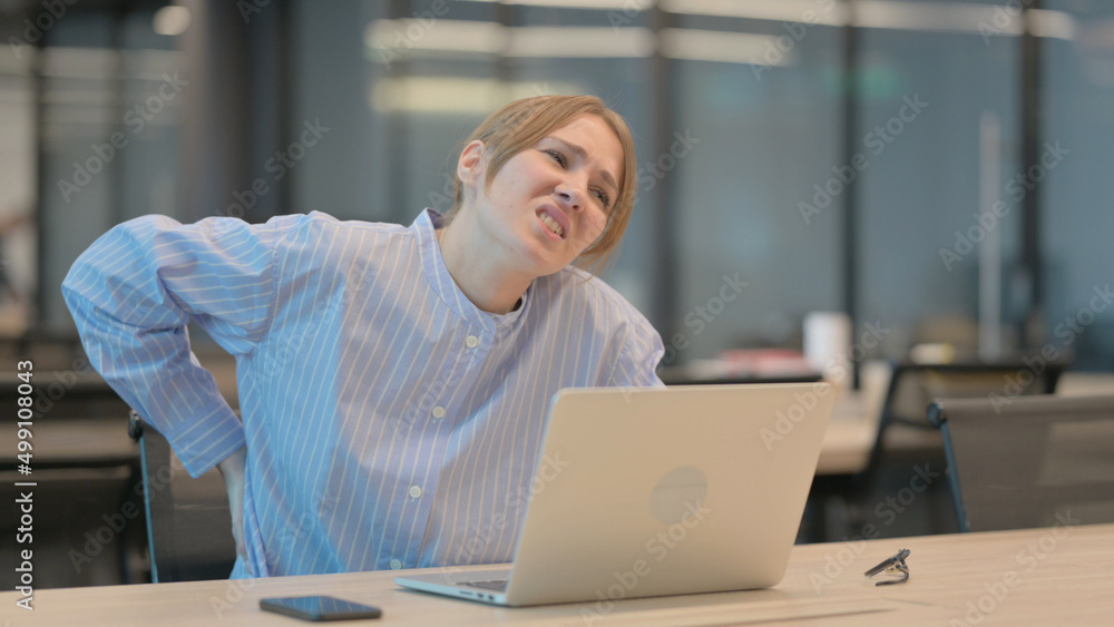 Young Woman having Back Pain while using Laptop in Office Young Woman having Back Pain while using Laptop in Office